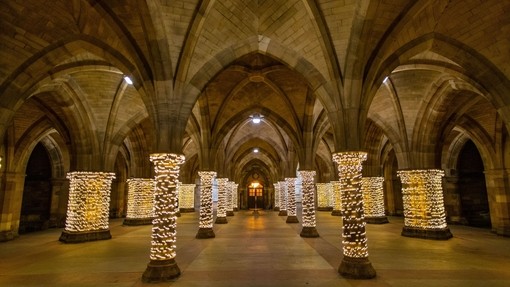 Fairy lights wrapped around pillars in a cloister at Glasgow University