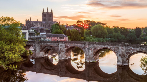 Roman Bridge over a river with a cathedral in background at sunrise