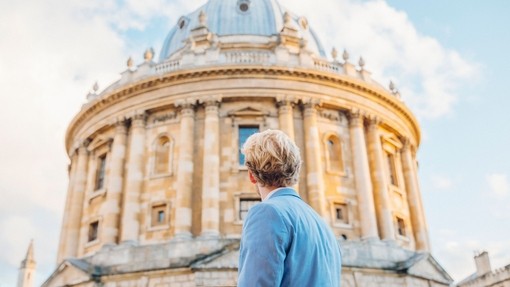 Man looking up at a historical building with domed shaped roof.