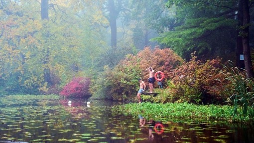 Two men on the swimming platform of a lake in an autumnal setting