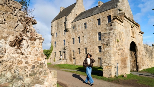 A woman walking through the grounds of a castle