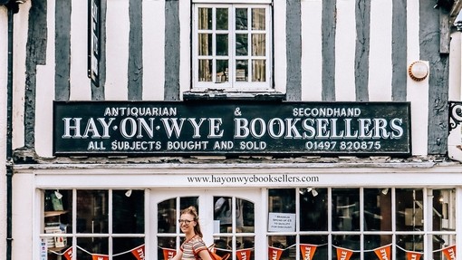 Young woman wearing backpack walks past bookshop