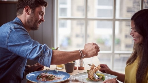 Couple sitting at a table, eating lamb beside a window