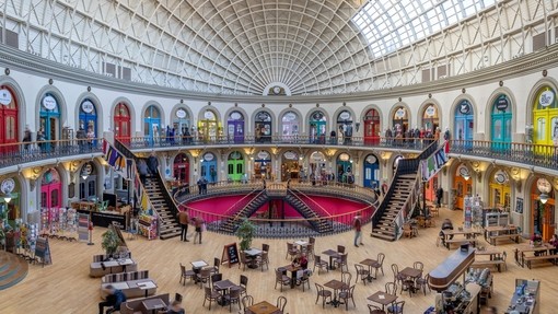 Inside a colourful domed building with people enjoying coffee and walking around the colourful building and stopping for coffee.