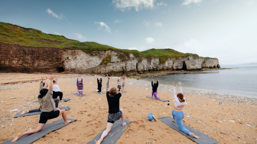 A group of people practising yoga on a beach