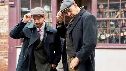 Two men posing on the street in front a hardware shop at living museum