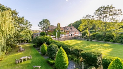 Aerial shot of a country house hotel, surrounded by manicured lawns with picnic tables.