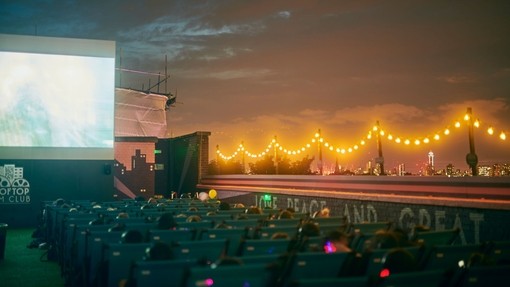 People watching a movie on a large screen at night with the city skyline in the distance
