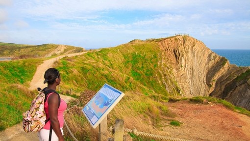 A woman reading an information board on the clifftop by the coast