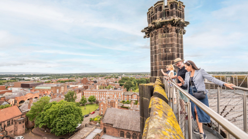 A group of people stand on a platform on the roof of a cathedral