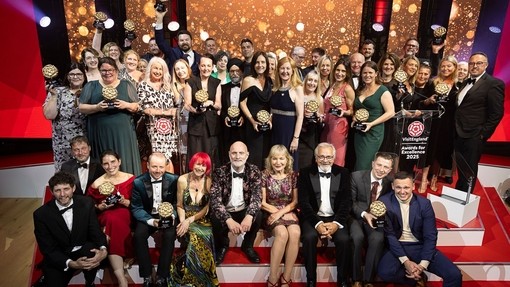 A group of winners on stage holding their awards at a gala ceremony.