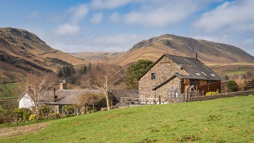 An external view across the field to some buildings, with the hills in the distance