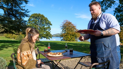 A man serves pizza to a woman