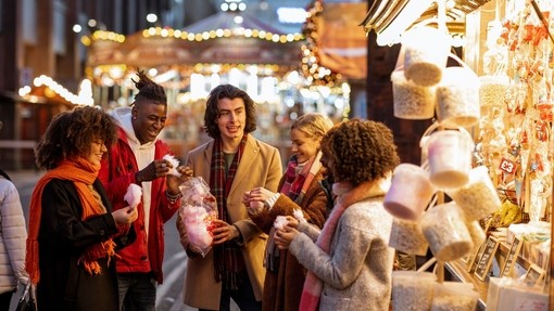 Group of young friends sharing a bag of cotton candy at the Christmas market.