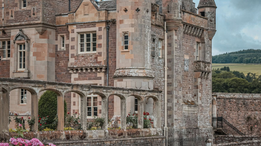 A woman twirling her dress in the gardens of a stately mansion.