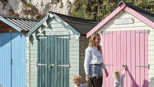 Woman and two children standing in front of pink beach hut