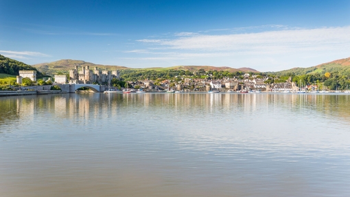 A view of a lake an village with an old castle in the background.