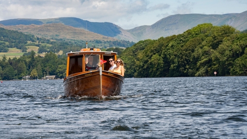 Visitors enjoying a boat tour on a lake with hills in the background