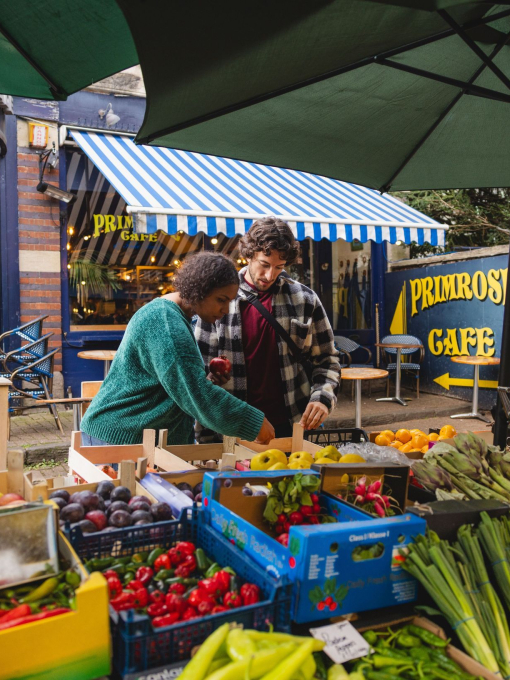 Friends shopping at a fruit & veg stall.