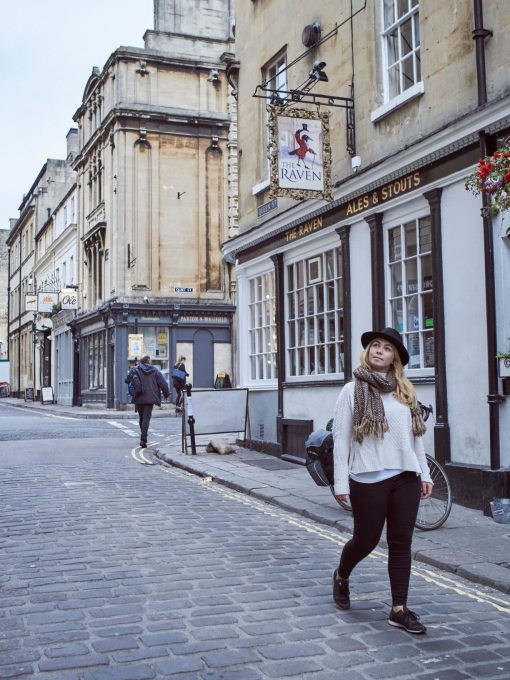 Woman walking on a road past a pub