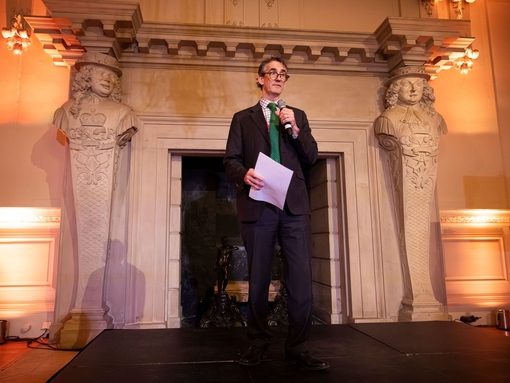 A man on a stage welcoming delegates at a trade event