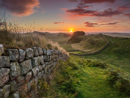 View along long stone wall over the fields at sunset
