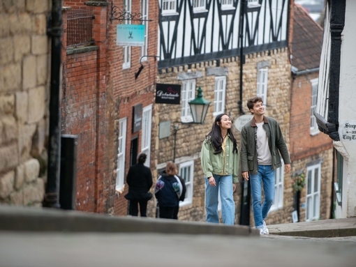 A woman and a man walk up a steep hill in a heritage City