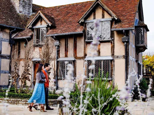 Couple walking through a garden of a Tudor building