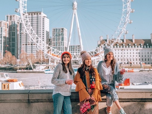 Three friends, sat on wall, with the London Eye behind