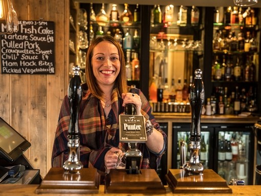 Woman serving drinks behind the bar in a pub
