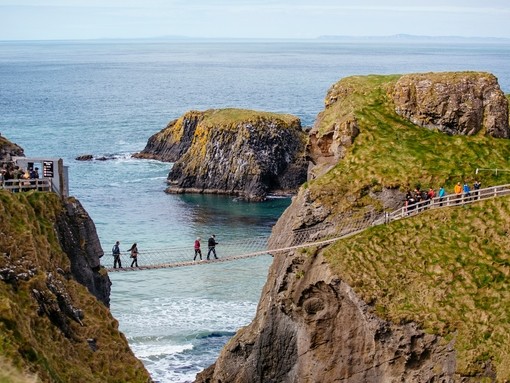Distant view of people crossing a rope bridge over the sea