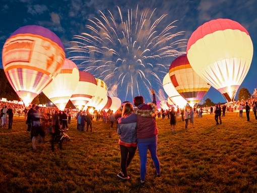 Lit up hot air balloons and fireworks in the night sky