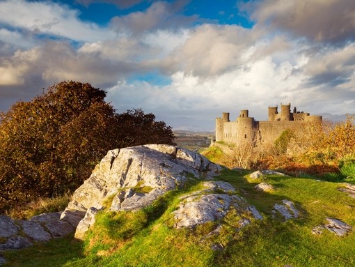 Harlech Castle standing on a grassy hilltop in North Wales. Blue skies and clouds