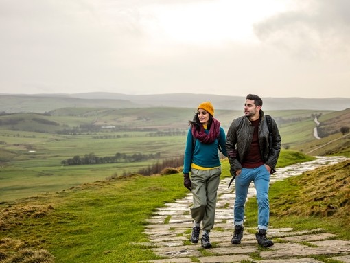 Young couple hiking and walking along a paved footpath.