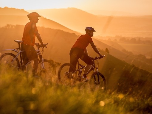 Two men on mountain bikes cycling at Devil's Dyke. Sunrise