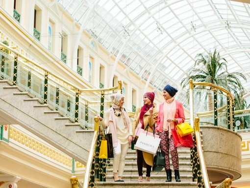 Three women, wearing scarves, walking with shopping bags