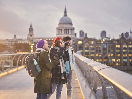 Friends standing on the Millennium Bridge, taking photos of the view