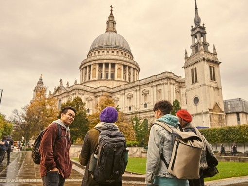 Four young people standing and talking on pavement