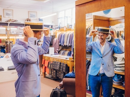 Man trying on a traditional straw boater hat in clothes shop