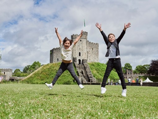Two children jumping in front of a castle