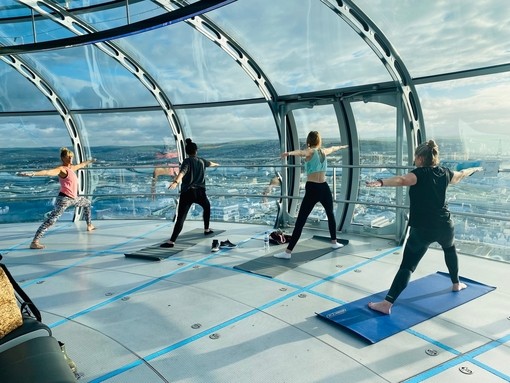 Female yoga class taking place on the viewing platform of British Airways i360 Viewing Tower, Brighton, East Sussex, England