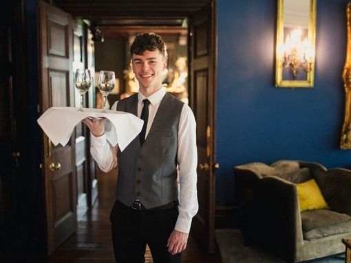 Waiter holding a tray with wine and smiling towards the camera
