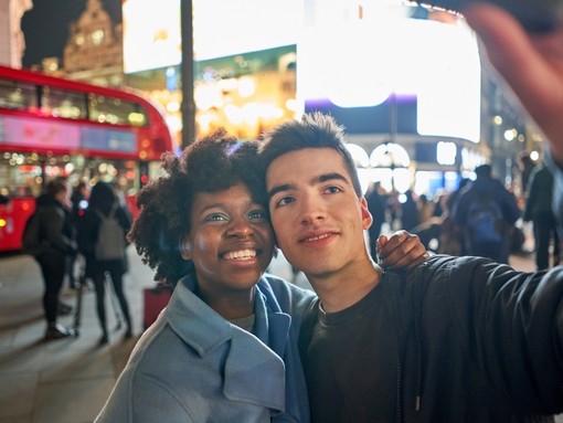 Young couple taking a selfie in the evening at Piccadilly Circus, London
