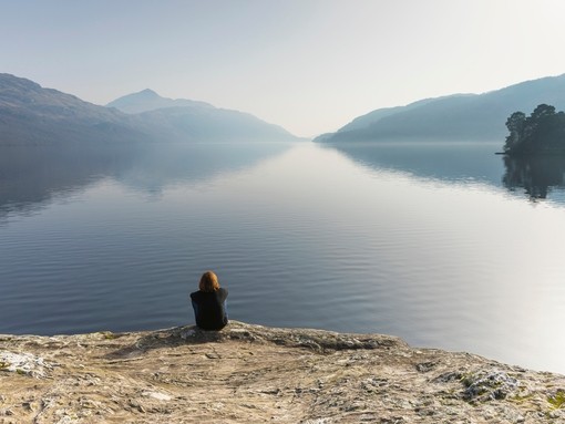 A woman sitting and looking out across Loch Lomond