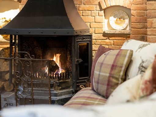 View of the lounge at Horseshoe Cottage Farm, Leicestershire close-up of the inglenook fireplace and tartan patterned sofas. Silver winner of the B&B and Guest House of the Year in the VisitEngland Awards for Excellence 2022