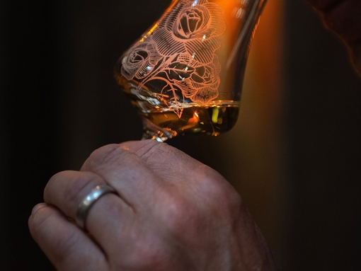 A person smelling whisky in a glass.