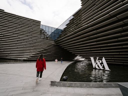 A woman and two girls walking by a modern museum.