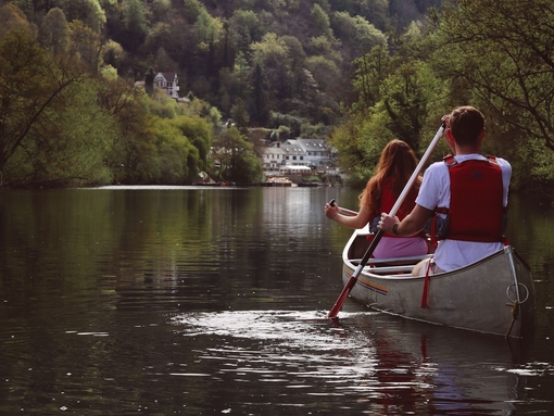 Two people canoeing along a river