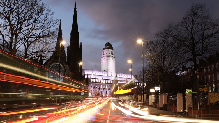 A view of a university taken from the street at night.