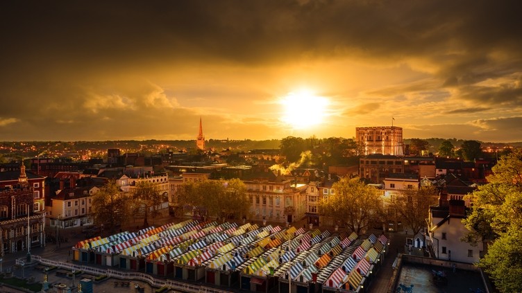 Aerial view of Norwich city centre showing colourful market stalls at sunrise